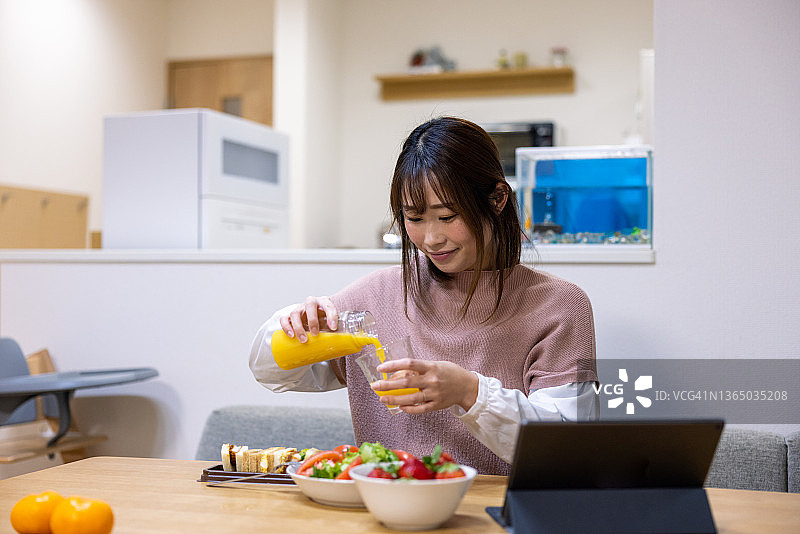 女人在家中倒橙汁作为午餐图片素材