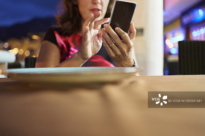 在市中心餐厅参加商务晚宴的美丽女人正面照。女人用手机给同事打电话图片素材
