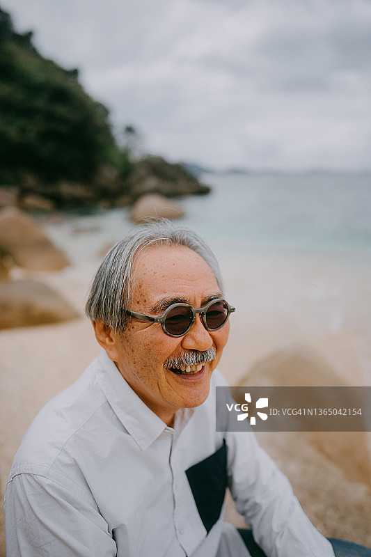 快乐的年长男人坐在沙滩上图片素材