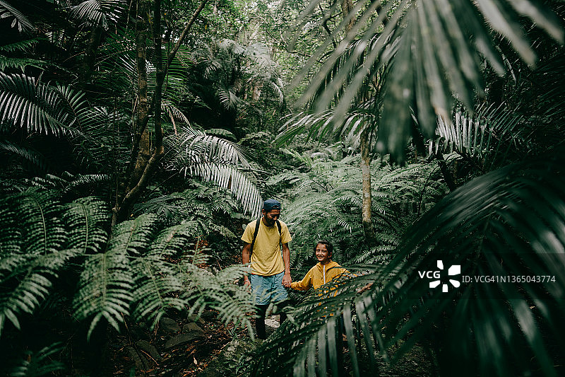 父亲和年幼的女儿在热带雨林中徒步旅行图片素材