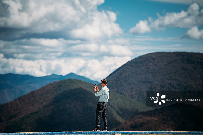 男子站在游泳池边，欣赏壮丽的山景图片素材