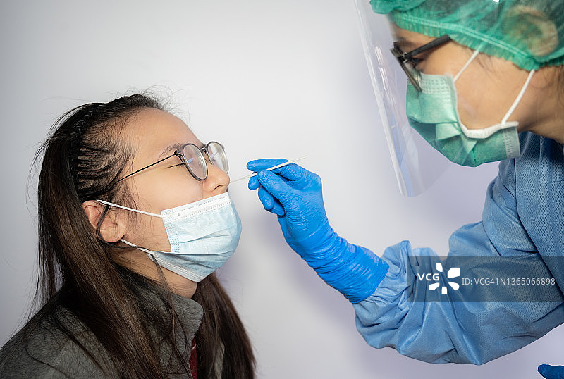 医护人员为亚洲女性进行新冠病毒检测的鼻拭子采样图片素材