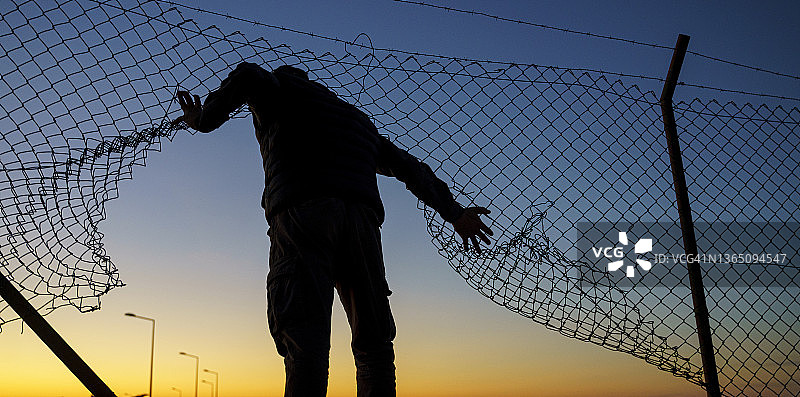 奔跑在栅栏后面的难民男子图片素材