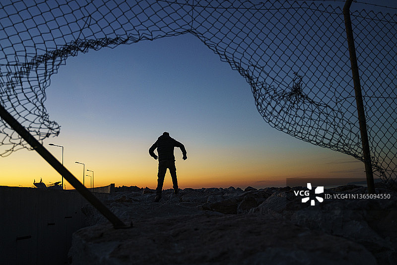 奔跑在栅栏后面的难民男子图片素材