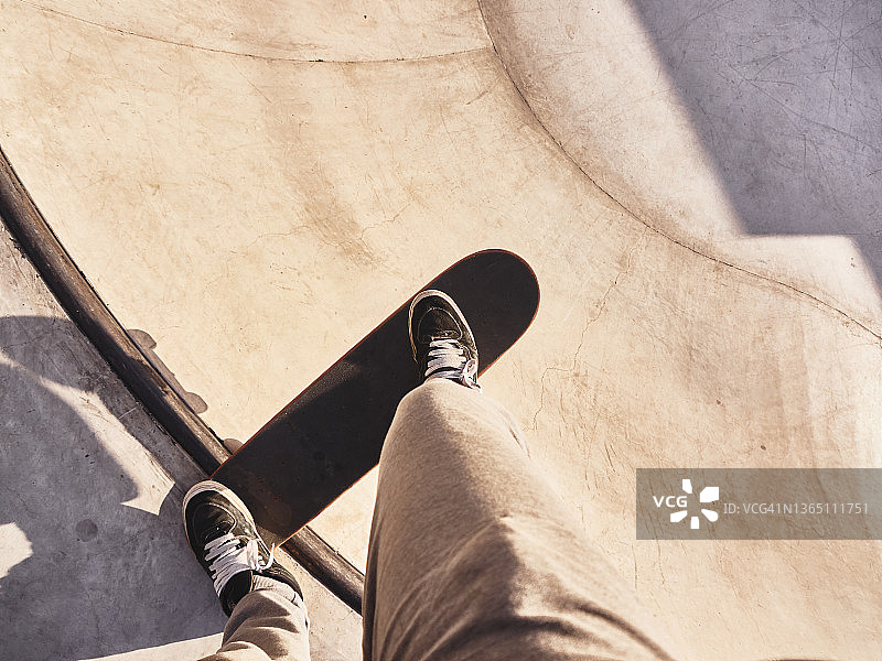 视角：滑板运动员的双脚踩在滑板上，准备滑下斜坡图片素材