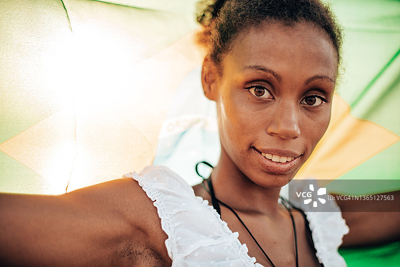 海滩上挥舞着巴西国旗的快乐女人图片素材