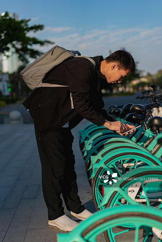 亚洲男人用手机扫描二维码解锁共享单车图片素材