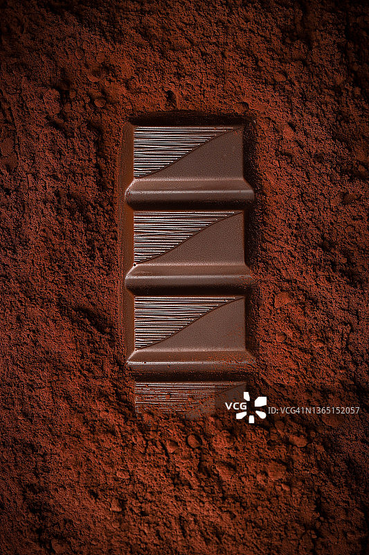 可可粉上的巧克力棒特写，深色背景图片素材