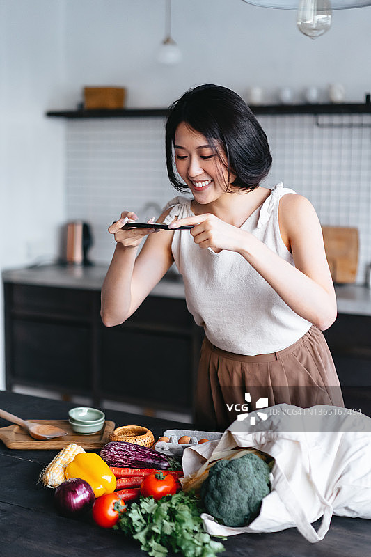 从购物回家后从购物袋里取出蔬菜水果的年轻亚洲女性图片素材