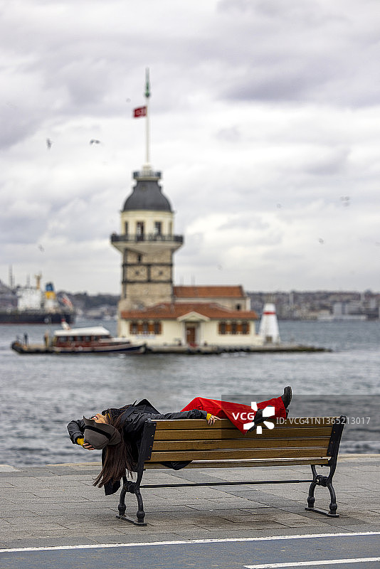 美丽女人在伊斯坦布尔少女塔前长凳上摆姿势图片素材