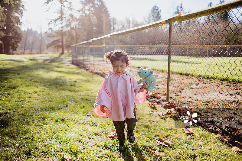 穿着粉色雨披的可爱2岁女孩在探险图片素材