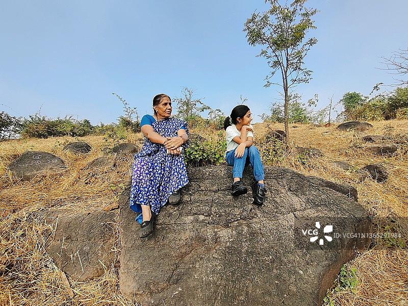 祖母和孙女在自然徒步中在岩石上休息图片素材