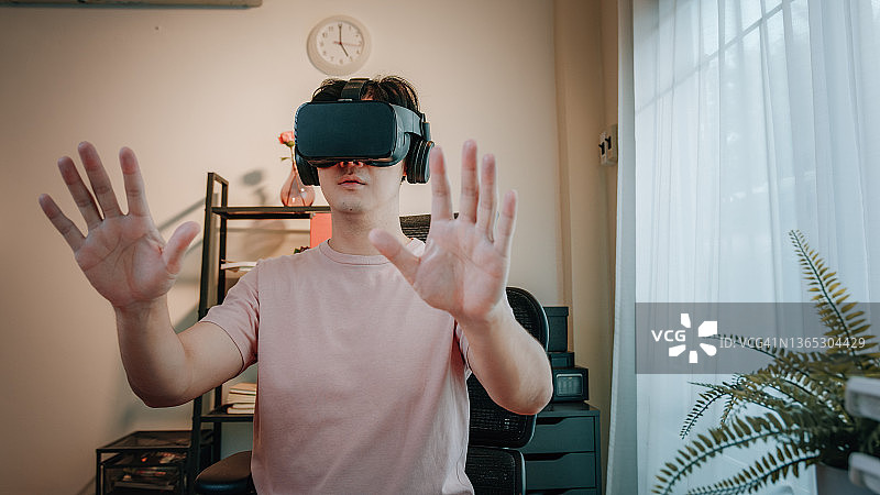 男子在家中使用虚拟现实眼镜在元宇宙数字网络世界中旅行图片素材