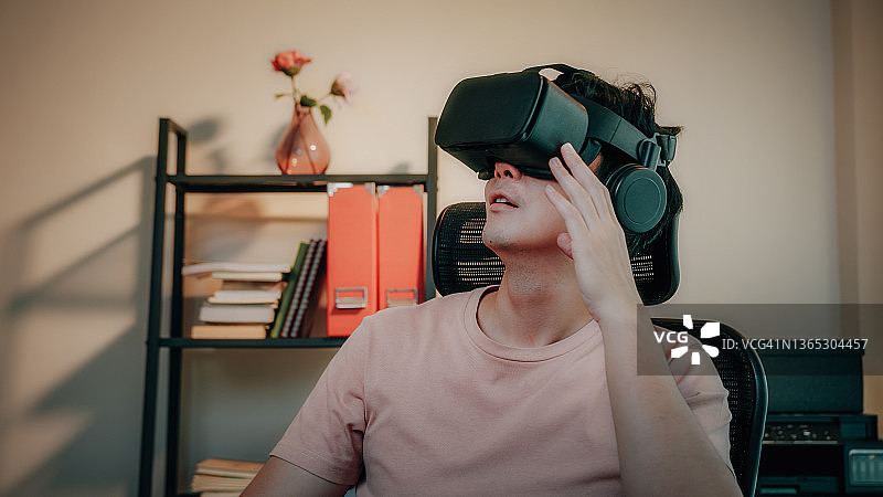 男子在家中使用虚拟现实眼镜在元宇宙数字网络世界中旅行图片素材