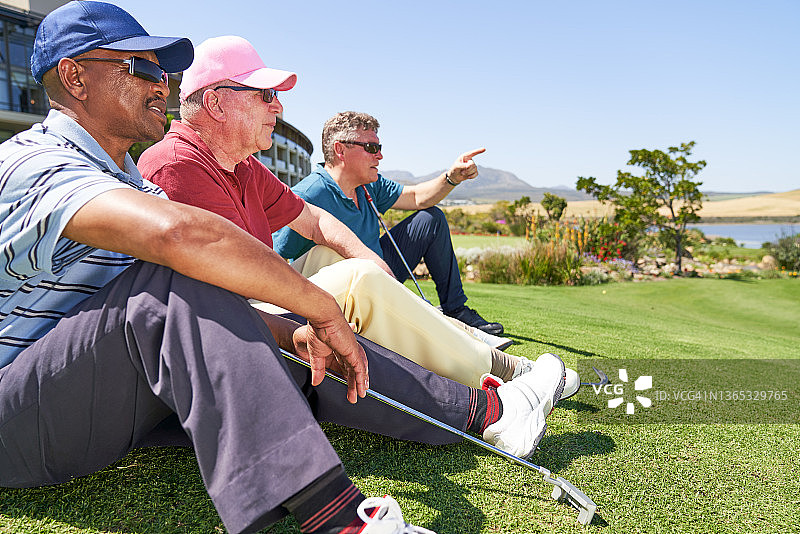 男性高尔夫球手坐在阳光明媚的高尔夫球场草地上休息图片素材