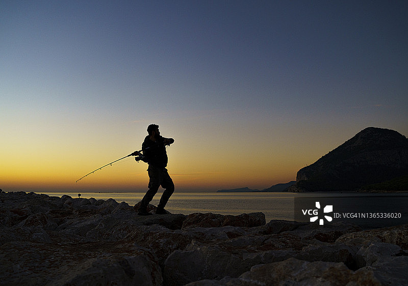 土耳其安塔利亚日出时钓鱼的年轻男子轮廓图片素材