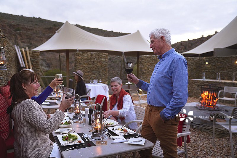 年长的男人在餐厅露台上与朋友举杯共饮图片素材