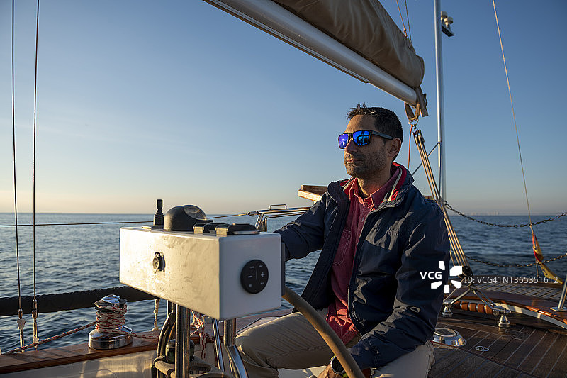 日出时分，男子扬帆航行图片素材