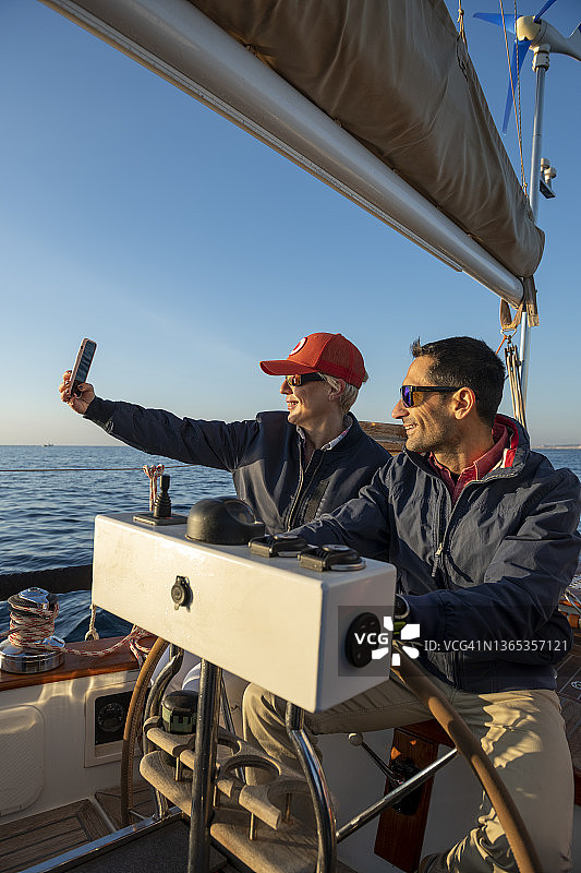 日出时分，年轻情侣在帆船上航行图片素材