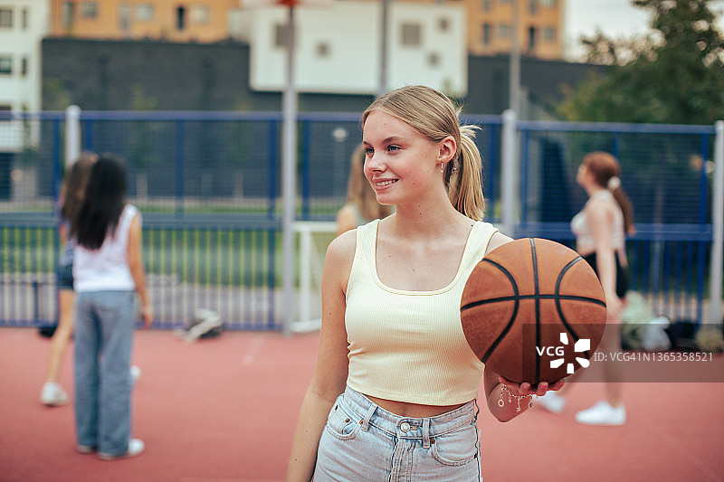 一个在户外篮球场快乐的女孩的肖像图片素材