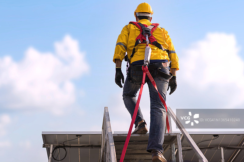 攀爬屋顶时佩戴安全带的建筑工人：高空作业安全图片素材