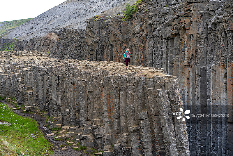站在冰岛Studlagil峡谷玄武岩柱顶端的女人图片素材