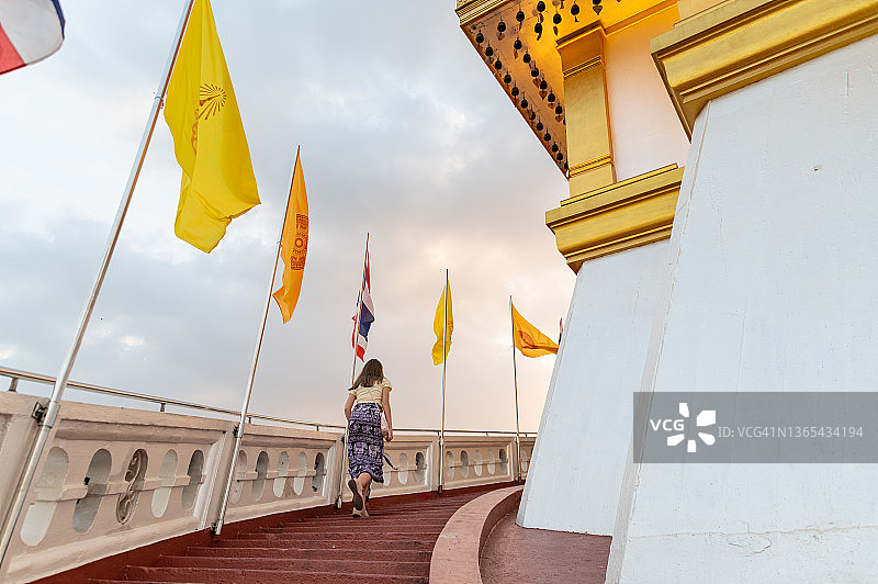 女孩爬上泰国曼谷市萨格寺（金山寺）顶端的楼梯图片素材