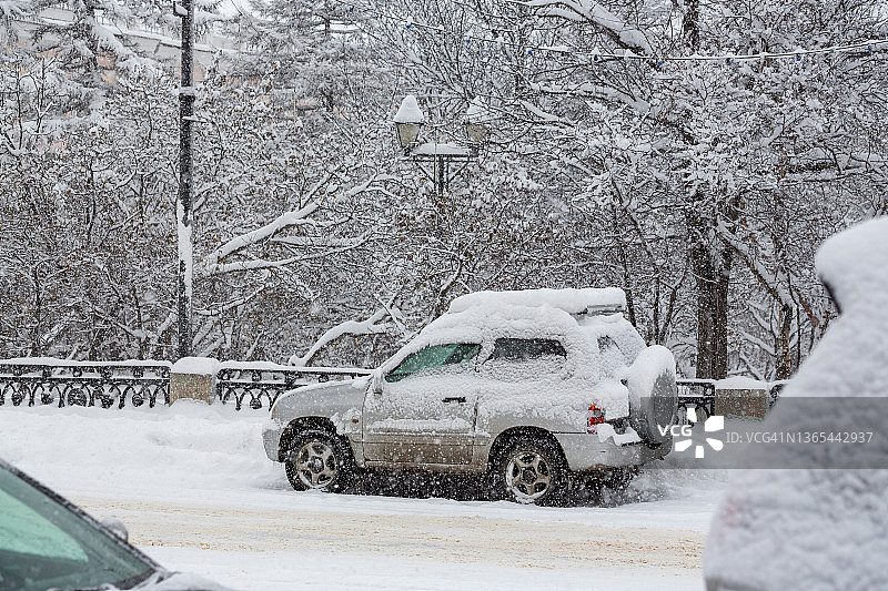 大雪期间城市街道上雪覆盖的汽车图片素材