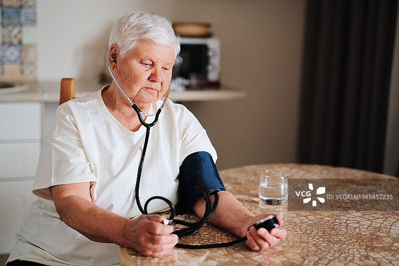 生病的老年妇女在厨房自行测量血压图片素材