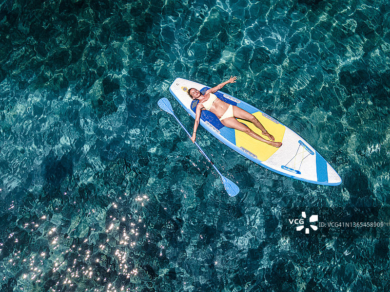 穿着比基尼在海上桨板上放松的中年妇女图片素材