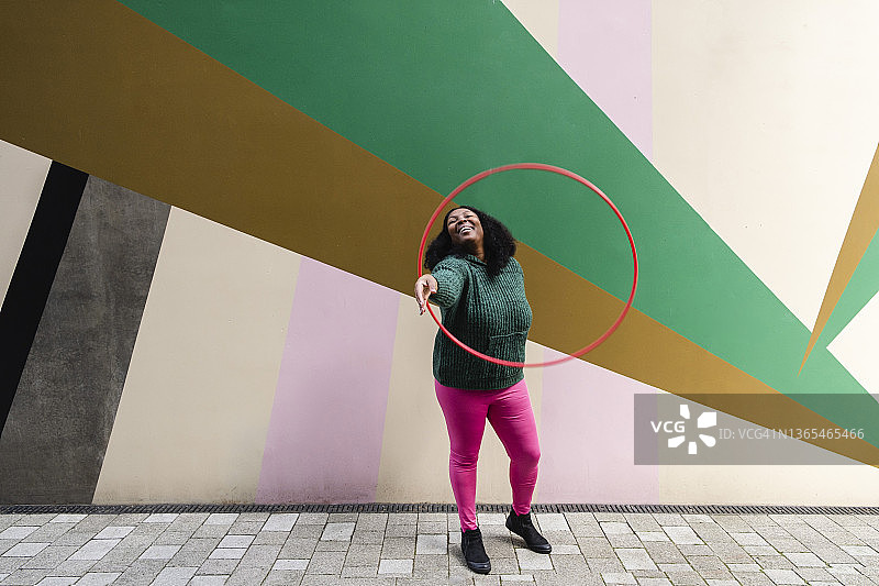 快乐的超重女人在人行道上玩塑料呼啦圈图片素材