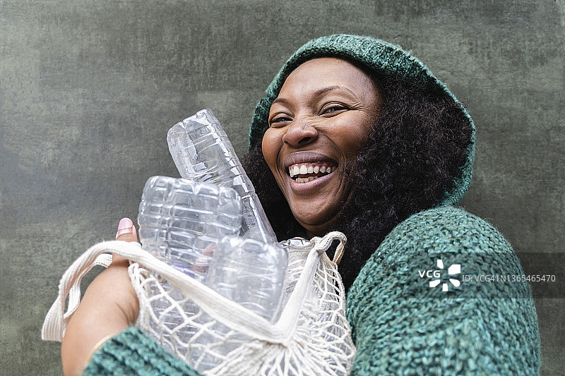 快乐的女人拿着装在网袋里的塑料水瓶图片素材