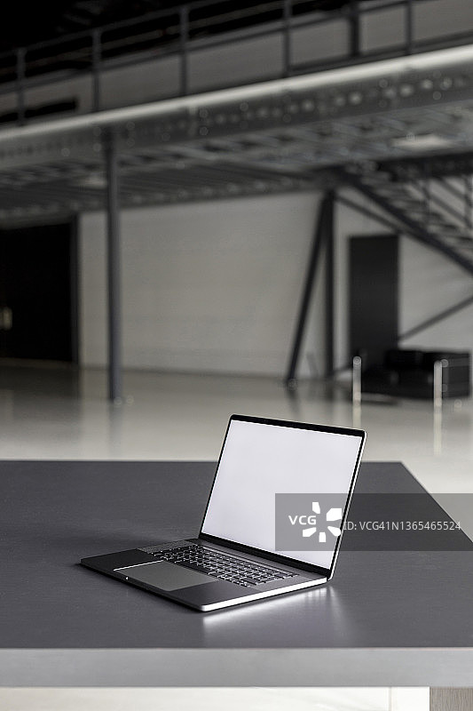 工业大厅办公桌上的空白屏幕笔记本电脑图片素材