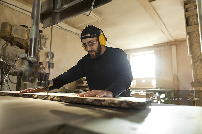 木工在车间用带锯锯木头图片素材
