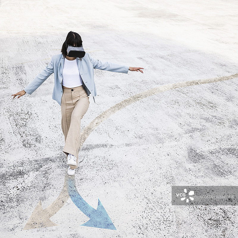 少女佩戴虚拟现实模拟器走在箭头符号上图片素材