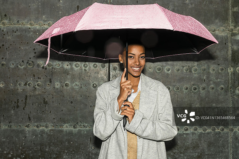 站在黑色墙前打着雨伞的少女图片素材