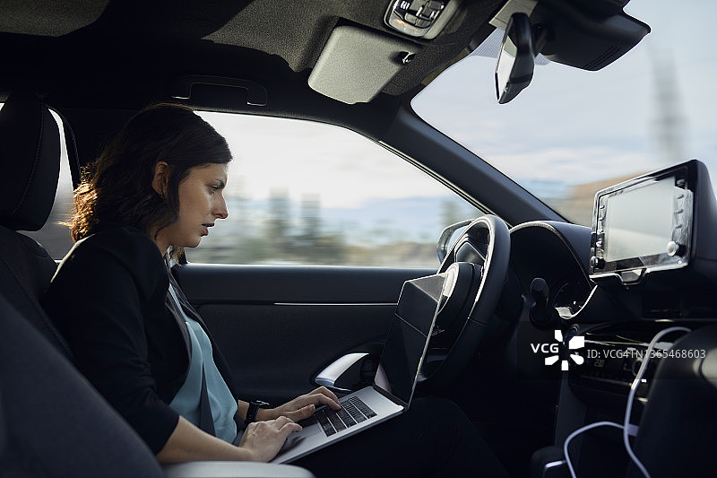 在无人驾驶汽车中使用笔记本电脑的女商人图片素材