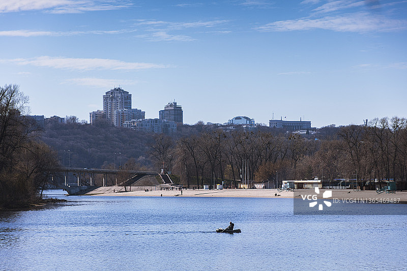 漂浮在第聂伯河蓝色水域的充气船上的身影轮廓，基辅市右岸景观图片素材