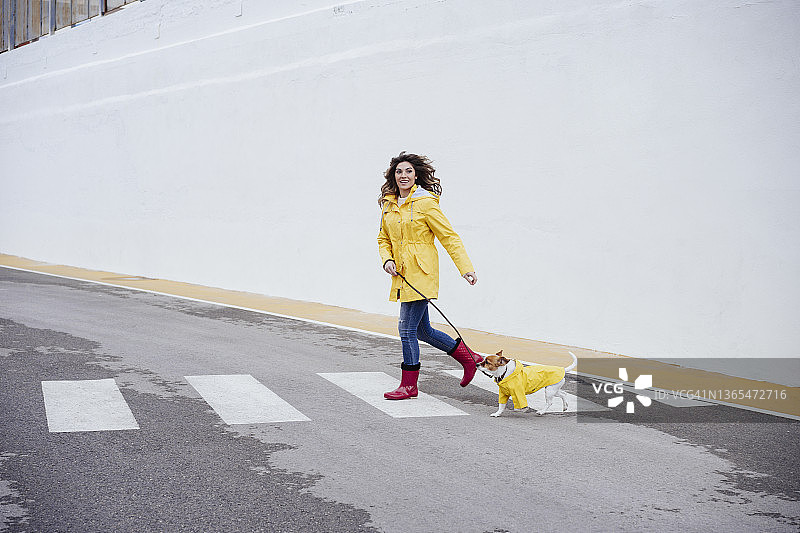 快乐的女人在人行横道上和狗一起奔跑图片素材