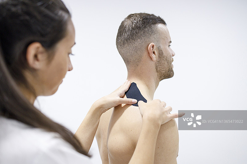 理疗师为运动员的肩膀贴治疗胶带图片素材