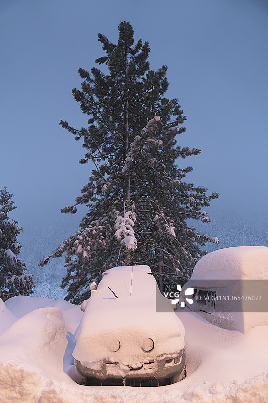 黄昏时分停在停车场的雪覆盖车辆图片素材