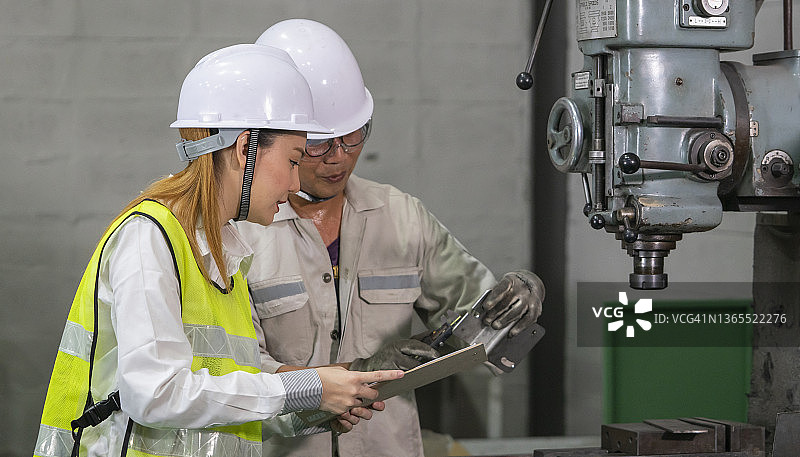 工厂车间内使用游标卡尺测量零件的工业工人图片素材