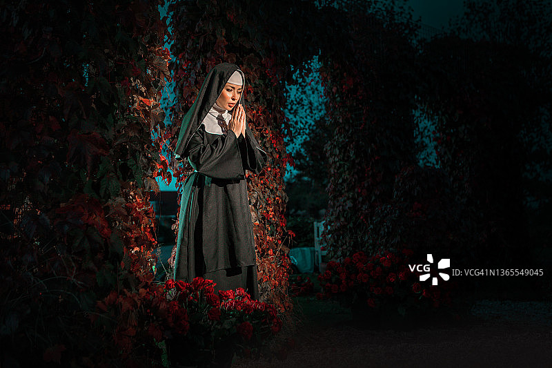 秘密玫瑰园中的美丽棕发修女图片素材