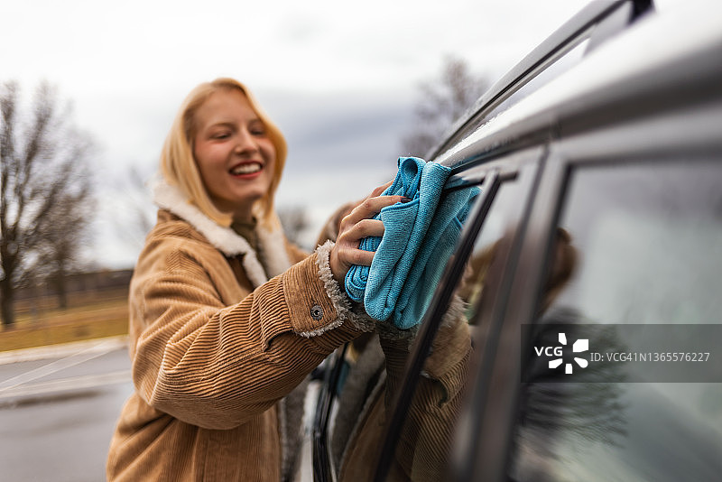 女人在洗车场用抹布擦拭白色汽车图片素材