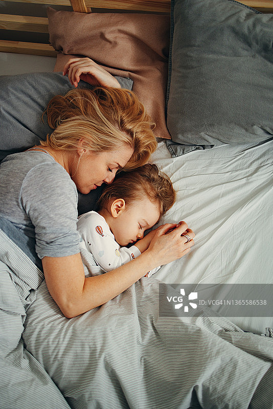 俯视角度拍摄的母亲和孩子在早晨舒适地侧睡图片素材
