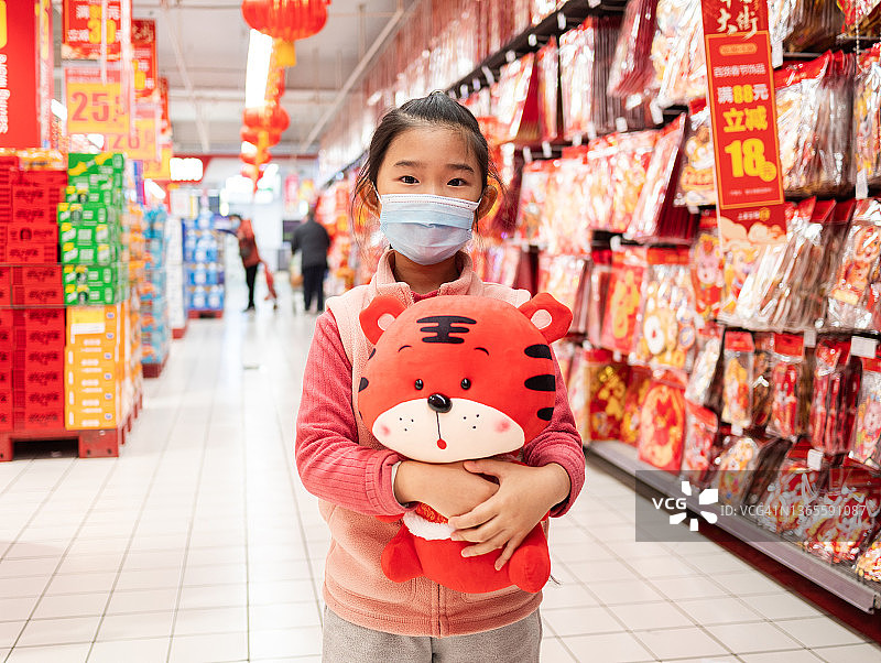 小女孩在超市抱着老虎毛绒玩具图片素材