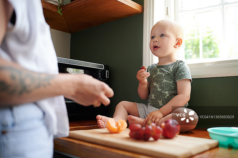 年轻女子在家为可爱的男婴准备饭菜图片素材