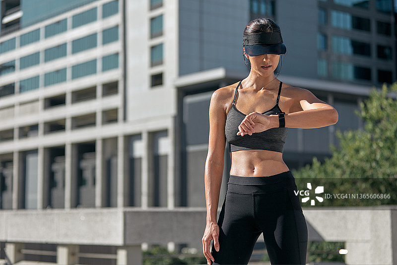 在城市锻炼的年轻女运动员查看手表图片素材