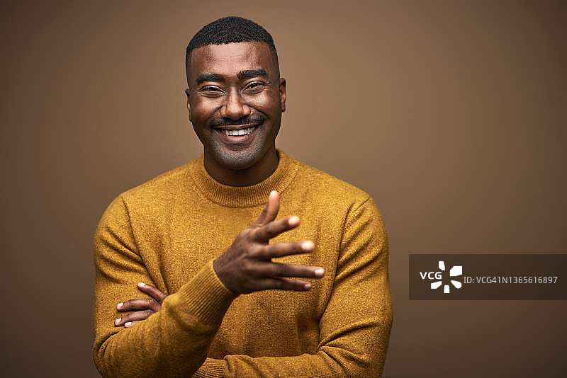在棕色背景下穿着毛衣的快乐男人图片素材