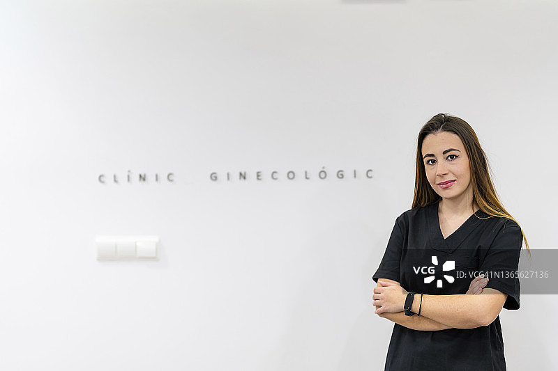 自信的接待员在诊所的白墙前交叉双臂站立图片素材